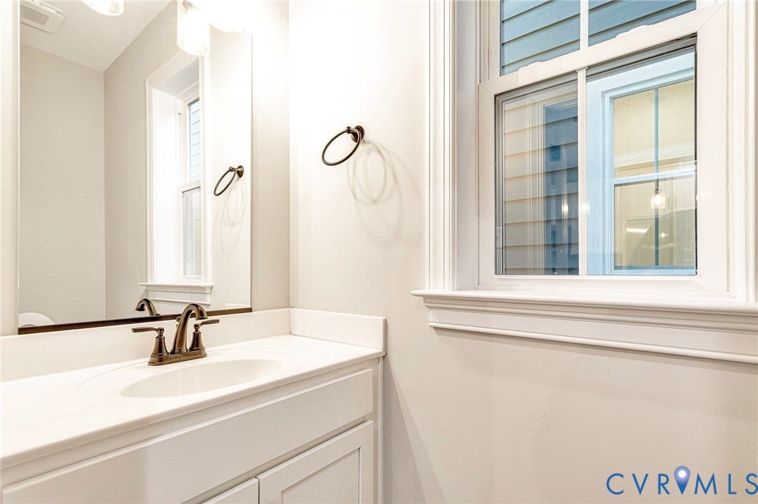 308 E 33rd Street, Swansboro West, Richmond, VA 23224 White vanity with cabinet storage, integrated sink, bronze-finish faucet, and coordinating towel ring