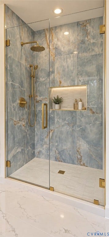 2695 High Bank Place, Powhatan, VA 23139 Glass-enclosed shower with blue-toned veined wall tile, brass-finish fixtures, a built-in recessed shelf with backlighting, and a tiled shower pan