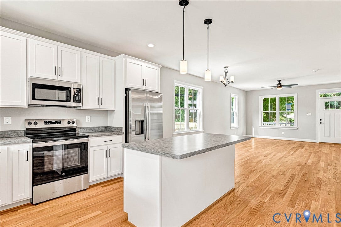306 E 33rd Street, Swansboro West, Richmond, VA 23224 Open-concept living space with wood-finish flooring, white cabinetry, stainless steel appliances, and a kitchen island with a stone countertop