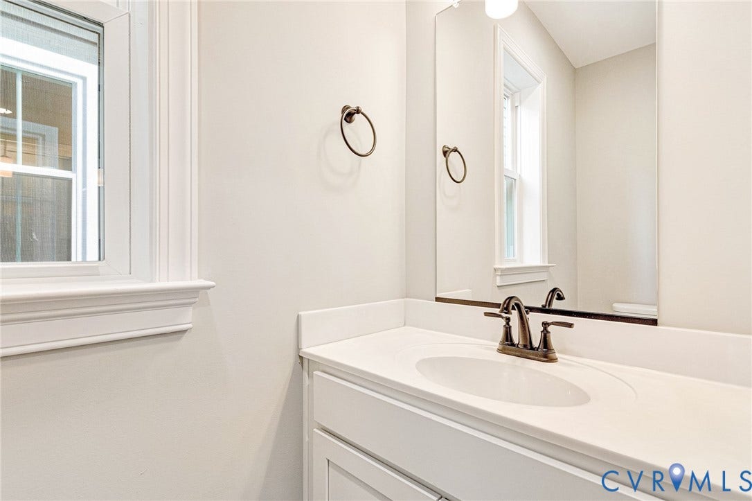 306 E 33rd Street, Swansboro West, Richmond, VA 23224 White vanity with integrated sink, bronze-finish faucet, and a large wall mirror