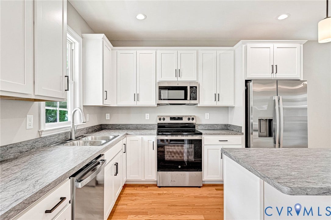 306 E 33rd Street, Swansboro West, Richmond, VA 23224 Kitchen featuring white cabinetry, stainless steel appliances, grey stone-finish countertops, a double basin sink, and wood-finish flooring