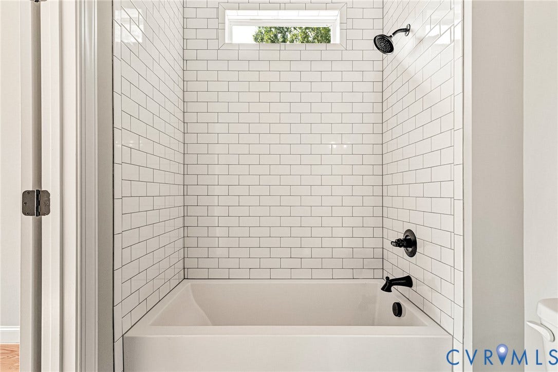306 E 33rd Street, Swansboro West, Richmond, VA 23224 Bathtub with white subway tile surround, dark-finished shower head, and dark-finished tub fixtures