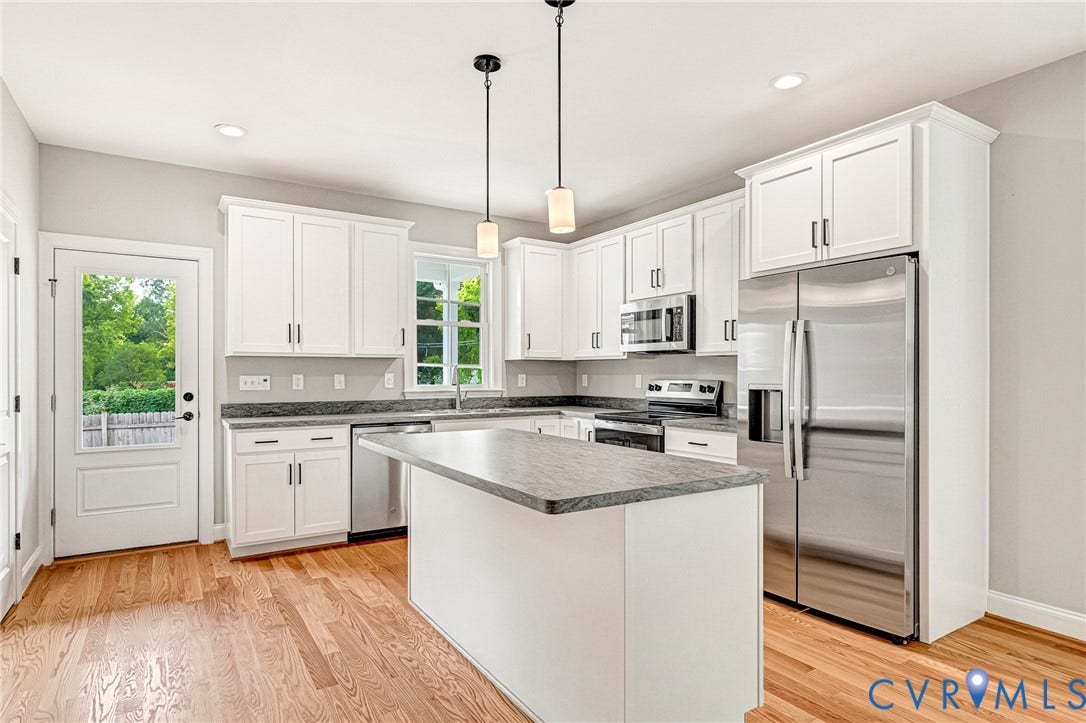 306 E 33rd Street, Swansboro West, Richmond, VA 23224 Kitchen featuring wood-finish flooring, white cabinetry, a central island, stainless steel appliances, and granite countertops