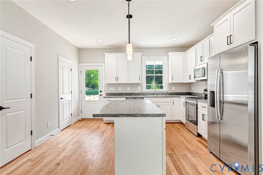 306 E 33rd Street, Swansboro West, Richmond, VA 23224 Kitchen featuring white cabinetry, stainless steel appliances, a center island with a stone countertop, and wood-finish flooring