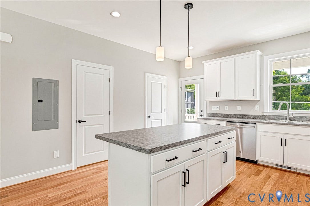 306 E 33rd Street, Swansboro West, Richmond, VA 23224 White cabinetry with black hardware, a center island featuring a gray countertop, stainless steel dishwasher, and wood-finish flooring