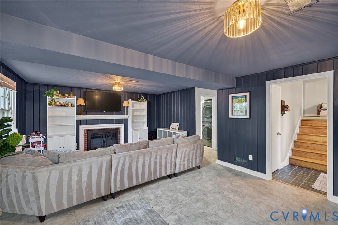 Room featuring wood paneling, a fireplace with a mantel, built-in shelving, and a ceiling fan