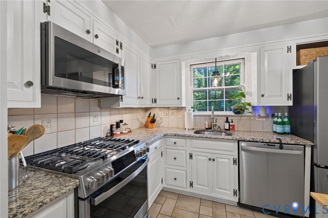 White cabinetry with dark hardware, granite countertops, tile backsplash, stainless steel appliances, and a window above the sink