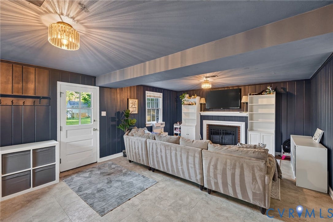 Fireplace with a white mantel, built-in shelving, glass-paned exterior door, recessed lighting, and paneling accents