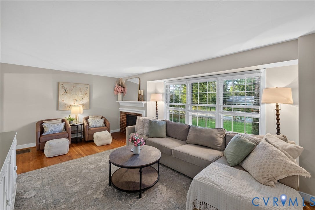 Hardwood flooring, white window frames, recessed fireplace with a white mantel, and light-toned wall paint