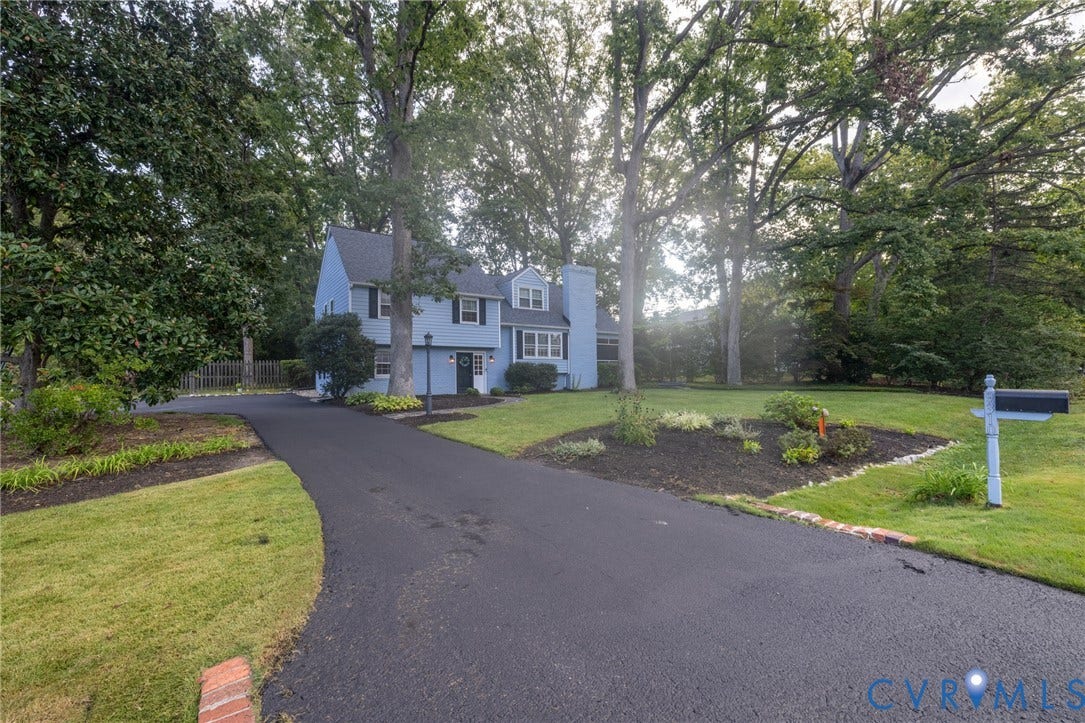 Two-story residence with light blue siding, black shutters, and a dark shingled roof