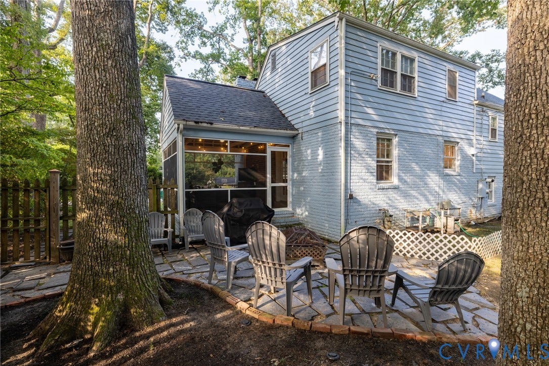 Screened porch with string lighting, stone patio, and mature trees