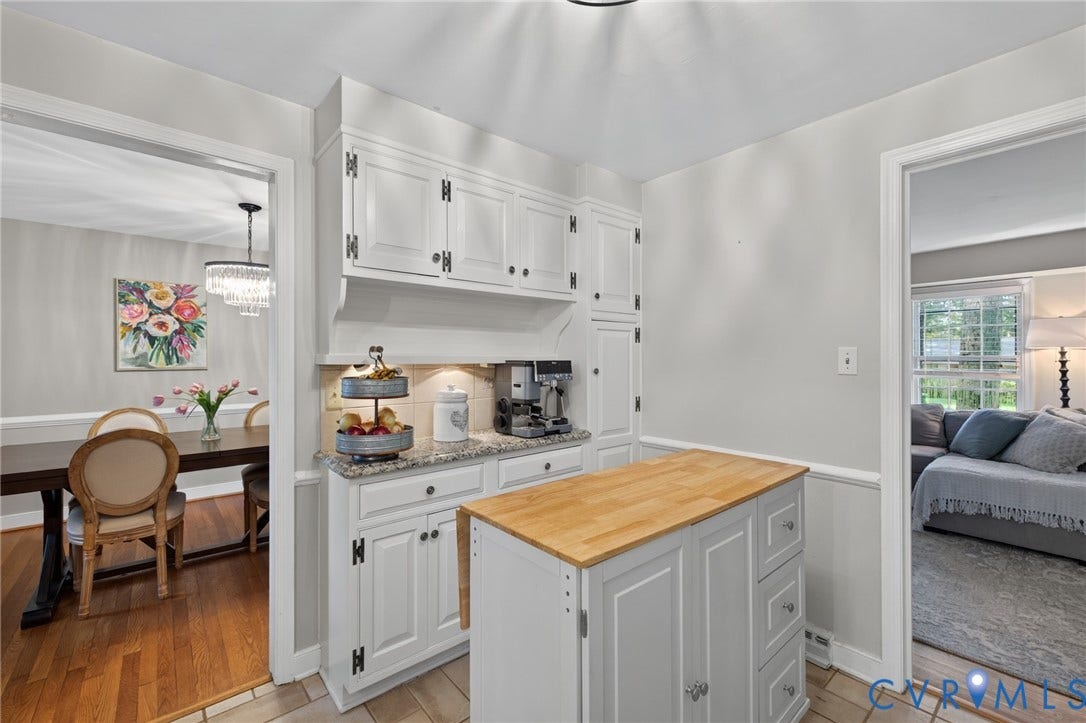 Kitchen with white cabinetry, granite countertops, tile flooring, and a portable butcher block island