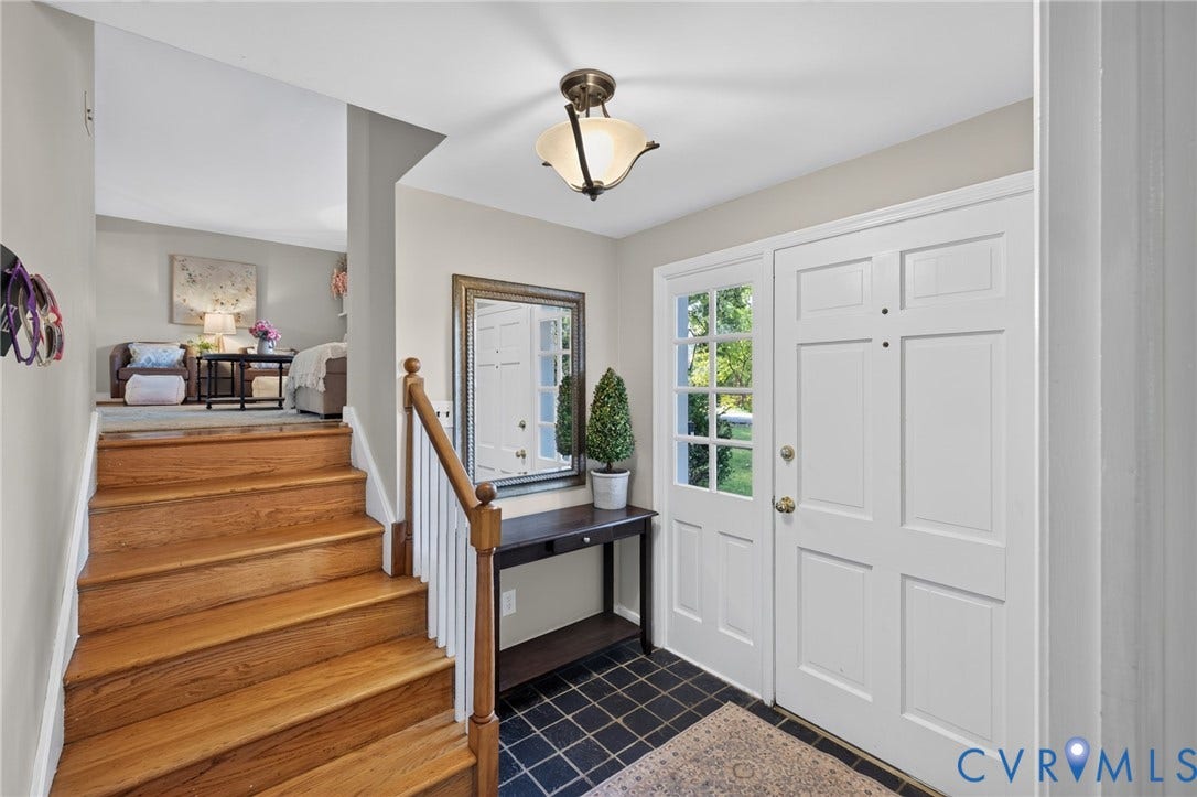 Entryway featuring a paneled front door, an adjacent sidelight, dark tile flooring, a wood staircase, and a ceiling-mounted light fixture