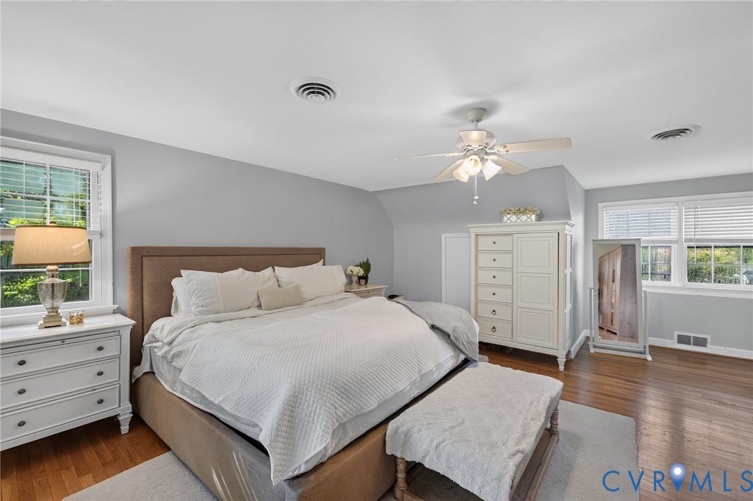 Hardwood flooring, multiple windows with blinds, ceiling fan with light fixture, and light gray wall paint
