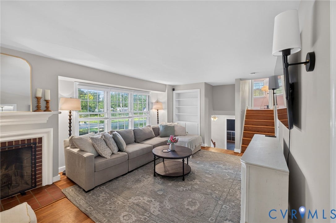 Living area with a brick-front fireplace, built-in shelving, wood-finish flooring, and multi-pane windows