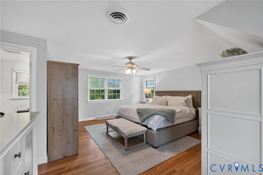 Hardwood flooring, multiple windows, ceiling fan with integrated lighting, built-in shelving, and white baseboards