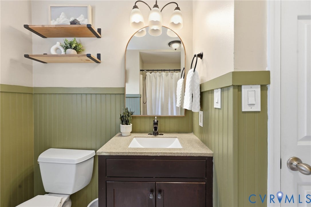 9349 Shiloh Drive, Chesterfield, VA 23237 Bathroom featuring a vanity with an integrated sink, dark wood-finish cabinetry, beadboard wall paneling, and two wood-finish floating shelves
