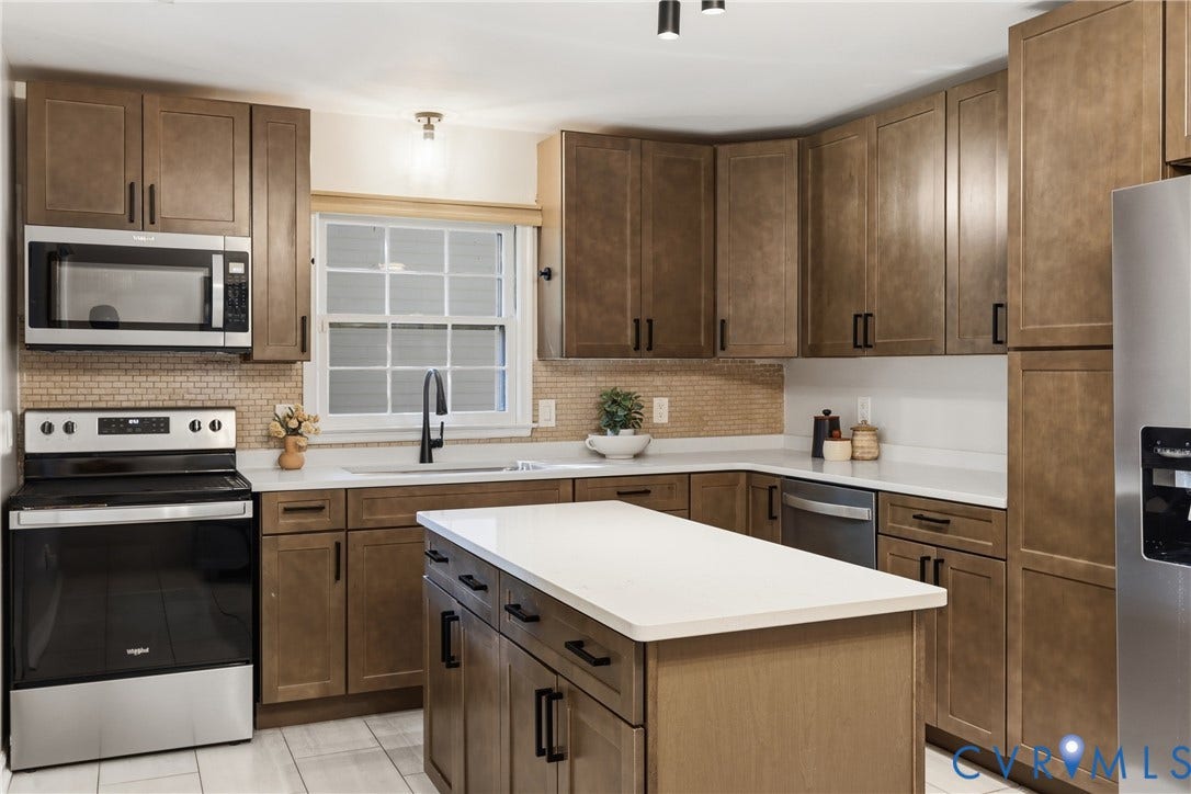 9349 Shiloh Drive, Chesterfield, VA 23237 Kitchen featuring wood-finish cabinetry, stainless steel appliances, a center island with a white countertop, and a tile backsplash