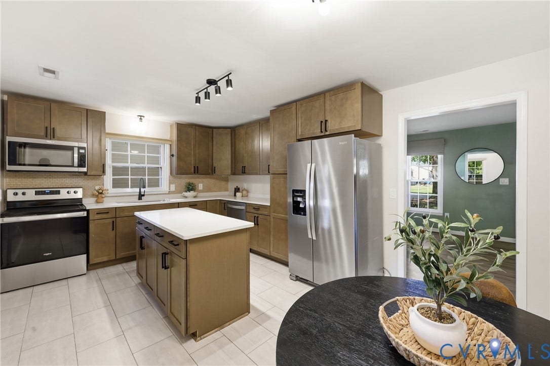 9349 Shiloh Drive, Chesterfield, VA 23237 Kitchen featuring wood-finish cabinetry, stainless steel appliances, a center island with a white countertop, and light-toned tile flooring
