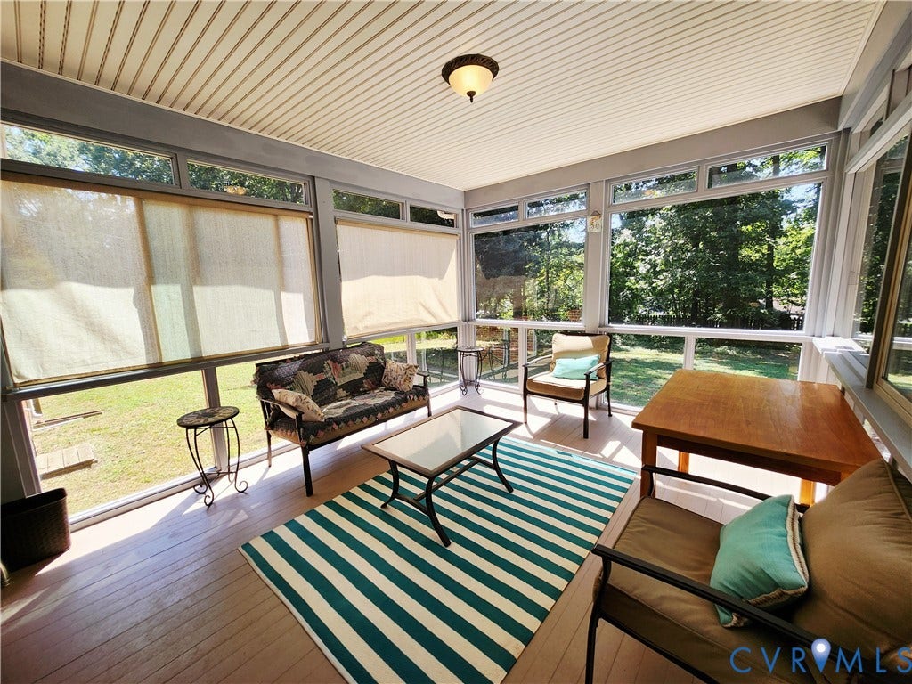 Screened porch with wood-finish flooring, full-height windows, overhead lighting, and window treatments
