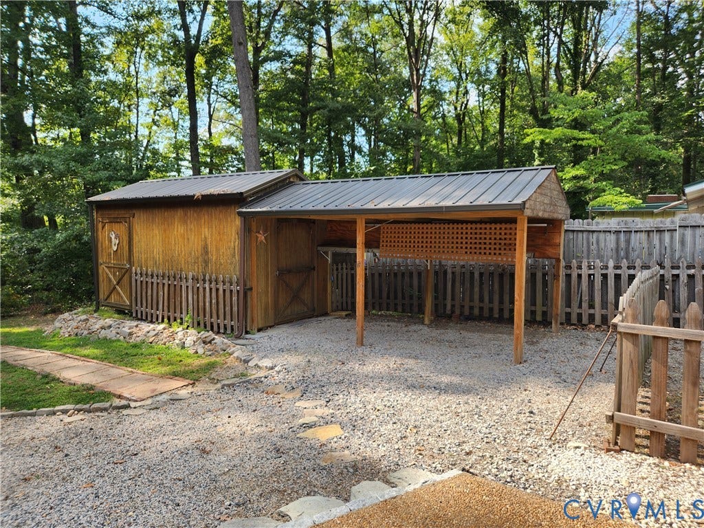 Wood-sided shed with a metal roof and attached wood-framed covered area, featuring a decorative lattice panel and gravel ground cover