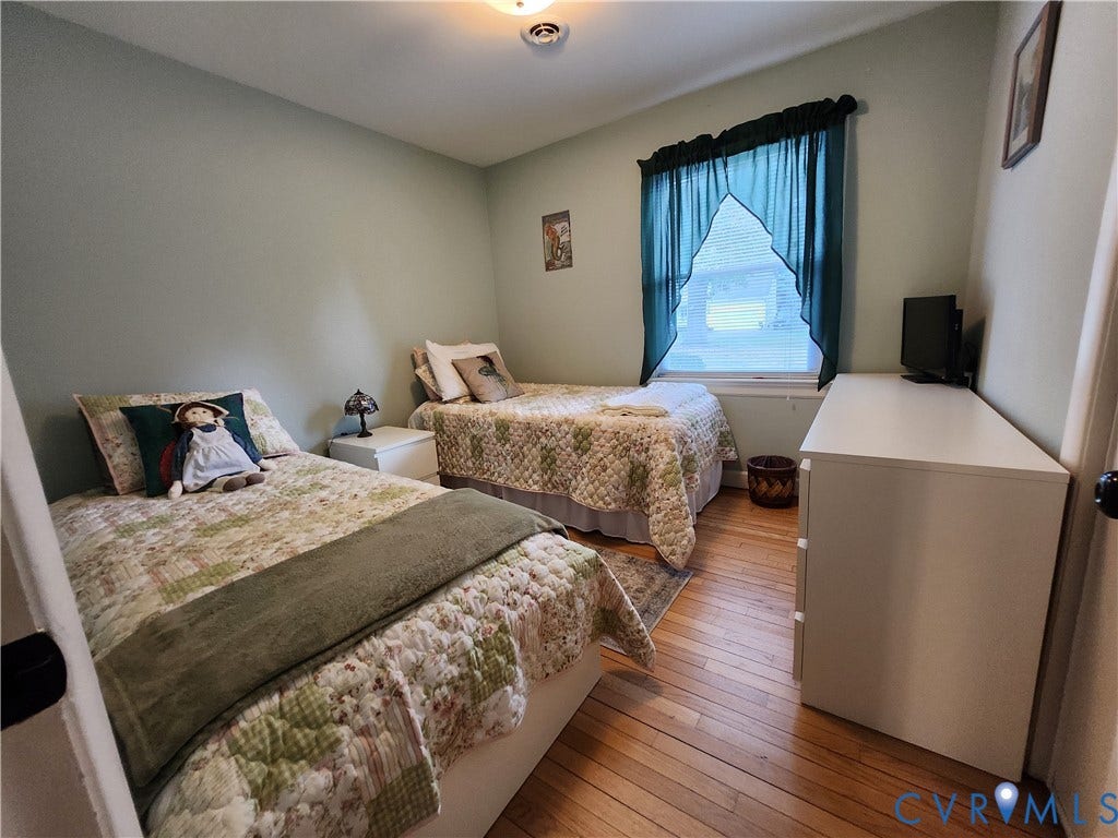 Wood-finish flooring, light-toned wall paint, and a window with a valance