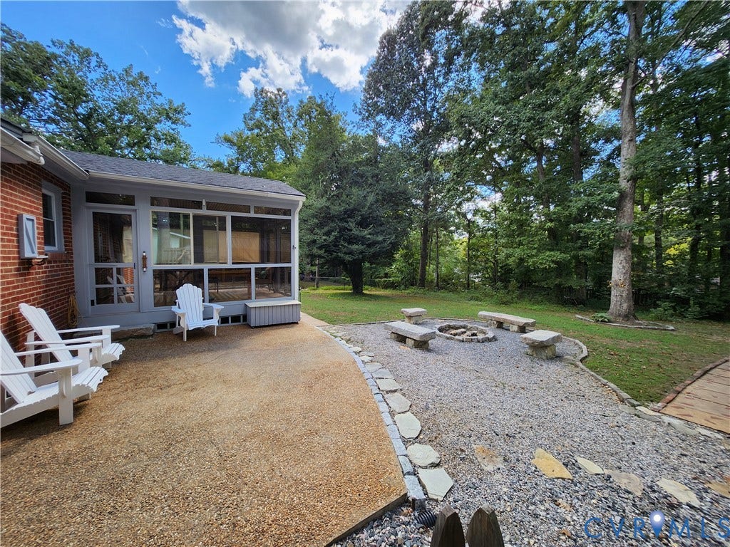 Screened porch with brick exterior, gravel patio, and stone fire pit area