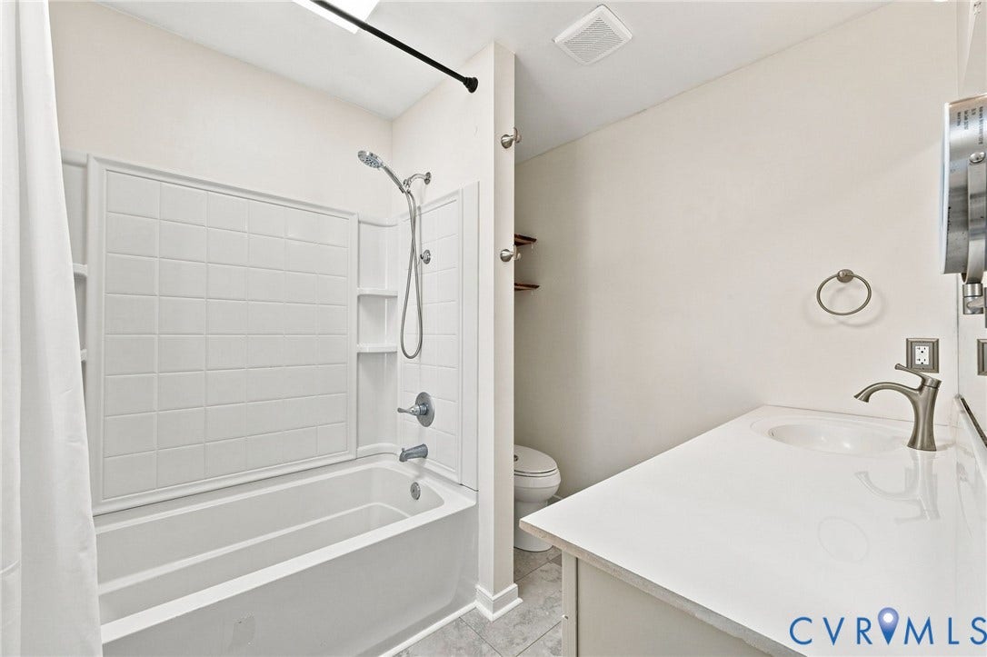 4509 Vienna Woods Place, Innsbrook, Henrico, VA 23060 White bathtub with tiled surround and integrated shelving, featuring a hand-held showerhead