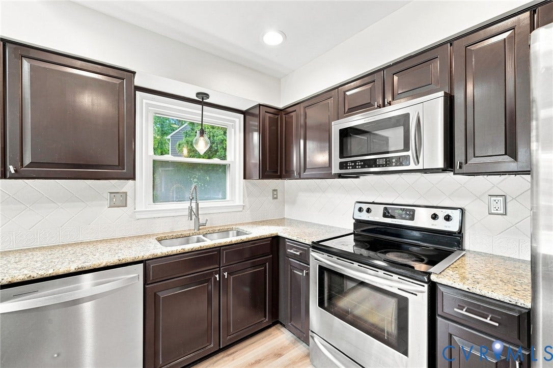 4509 Vienna Woods Place, Innsbrook, Henrico, VA 23060 Kitchen featuring dark wood cabinetry, light-toned countertops, stainless steel appliances, a double basin sink, and a patterned tile backsplash