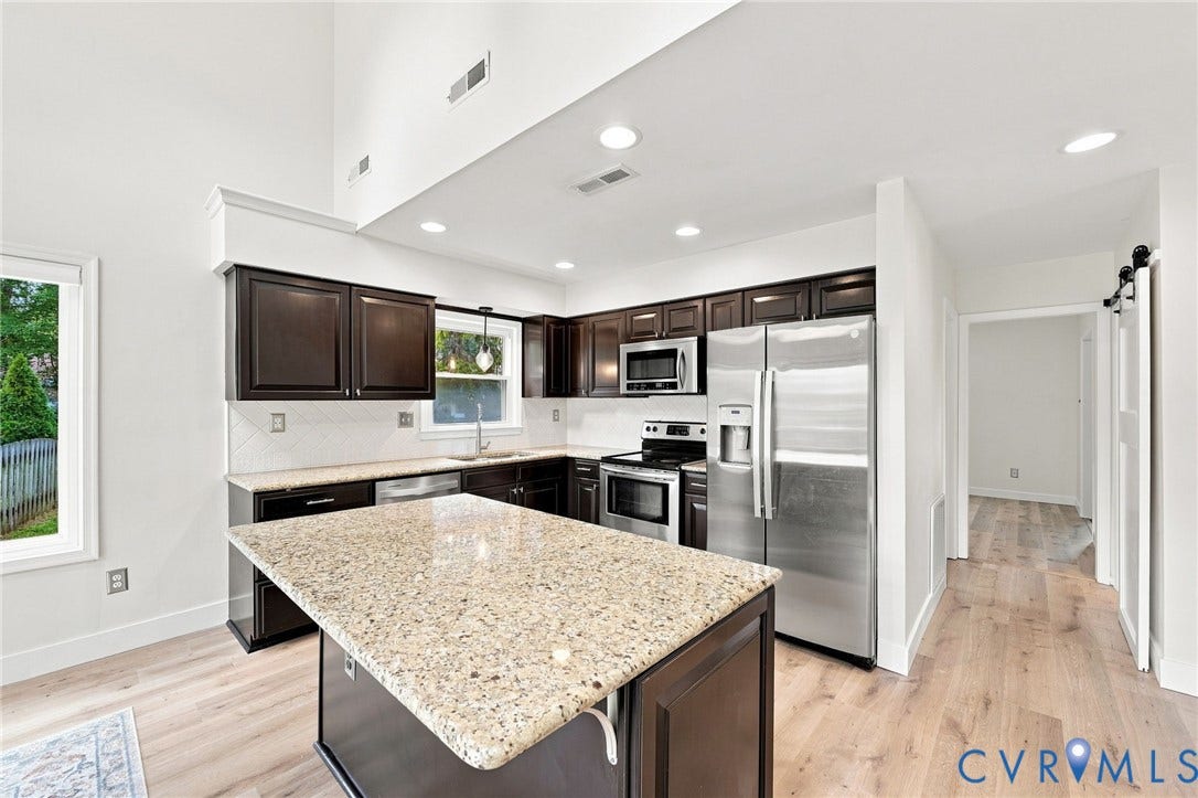 4509 Vienna Woods Place, Innsbrook, Henrico, VA 23060 Vaulted ceiling kitchen featuring dark wood cabinetry, stainless steel appliances, a light-toned island with a stone countertop, and light wood-finish flooring