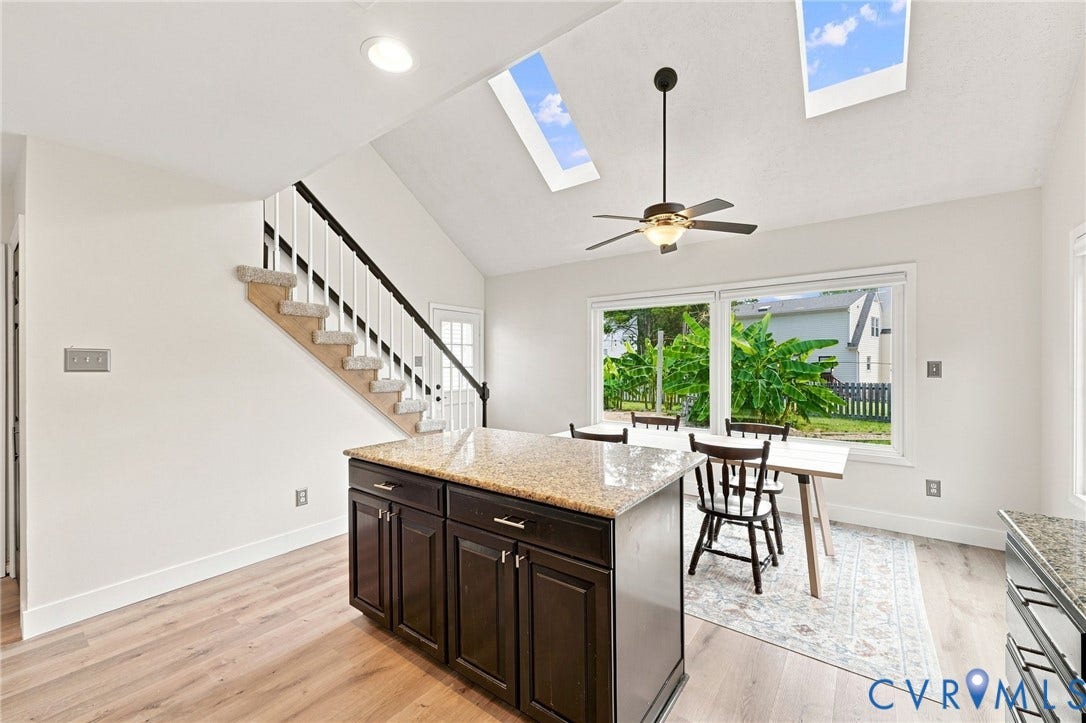 4509 Vienna Woods Place, Innsbrook, Henrico, VA 23060 Wood-finish flooring, vaulted ceiling with skylights, central island with stone countertop, staircase with carpeted treads, and built-in ceiling fan with lighting