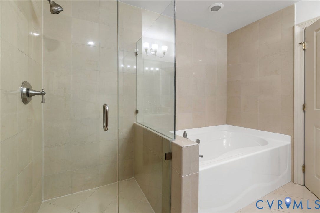6 N 6th Street, #U5B, Downtown/Financial District, Richmond, VA 23219 Glass-enclosed shower with brushed nickel fixtures, a white soaking tub, and neutral-toned wall tiling