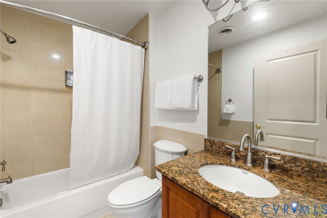 6 N 6th Street, #U5B, Downtown/Financial District, Richmond, VA 23219 Bathroom featuring a bathtub with an integrated shower, a vanity with a stone countertop, an undermount sink, and a framed mirror