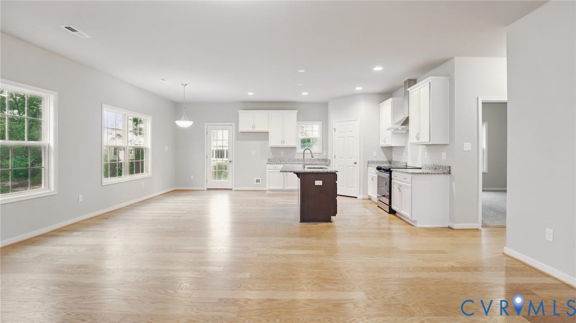 Open concept living area featuring wood-finish flooring, white cabinetry, granite countertops, a kitchen island, and recessed lighting
