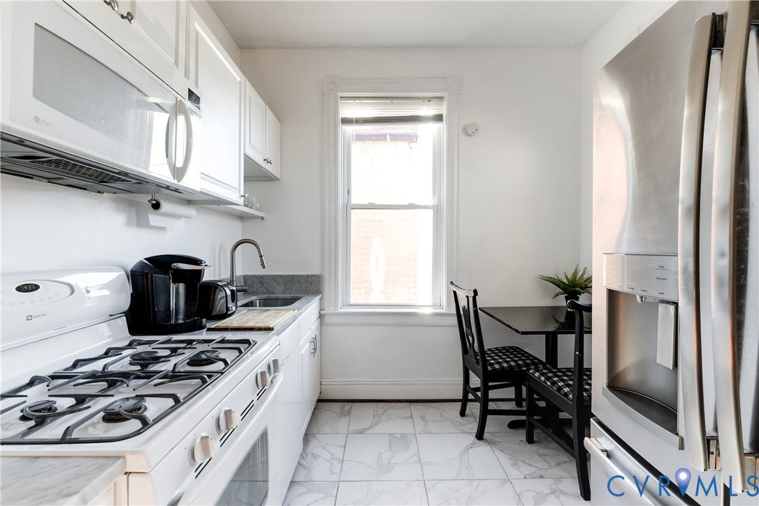 2523 W Main Street, The Fan, Richmond, VA 23220 White cabinetry with brushed nickel hardware, stainless steel refrigerator with integrated dispenser, gas range, undermount sink, and marble-finish tile flooring
