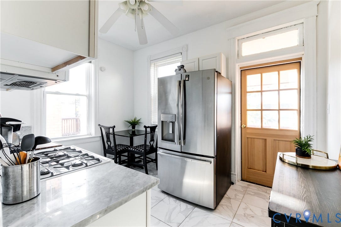2523 W Main Street, The Fan, Richmond, VA 23220 Stainless steel refrigerator, gas range, marble-look countertops, white cabinetry, and wood-finish door with transom window