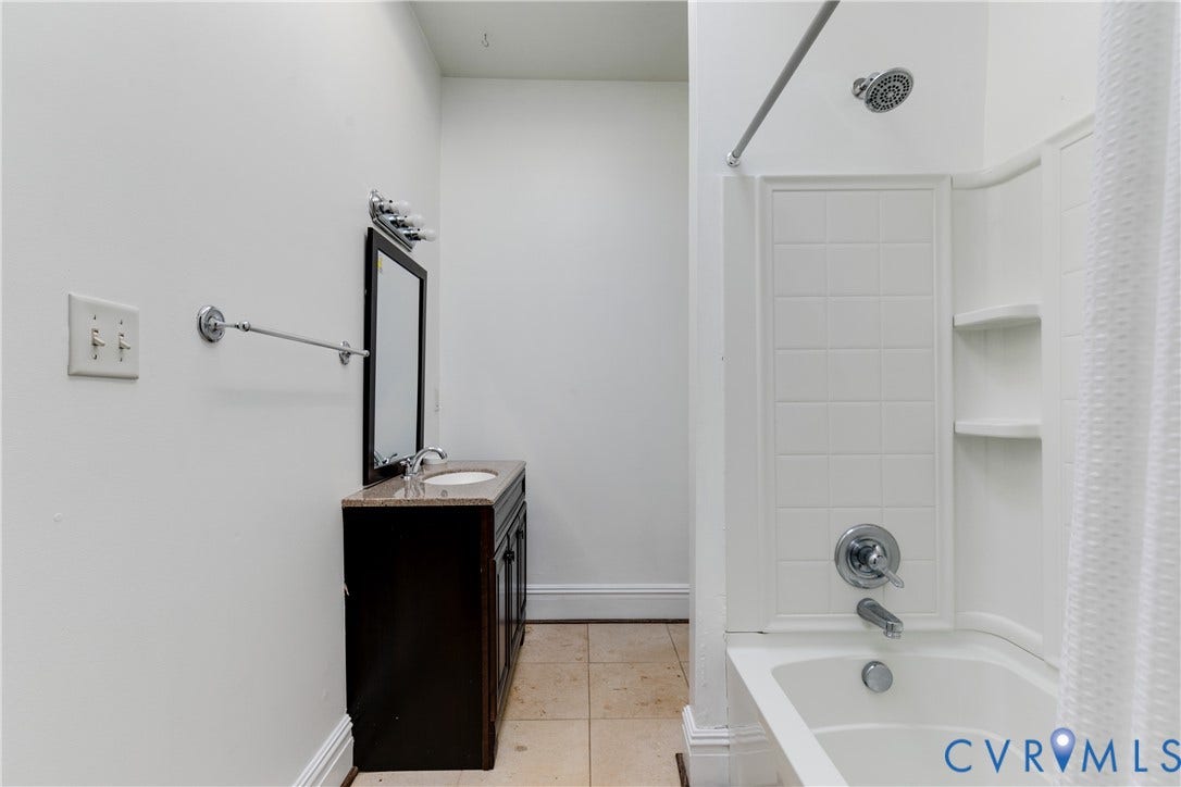 2523 W Main Street, The Fan, Richmond, VA 23220 White subway tile shower surround with integrated shelving, chrome shower fixtures, and a shower curtain rod