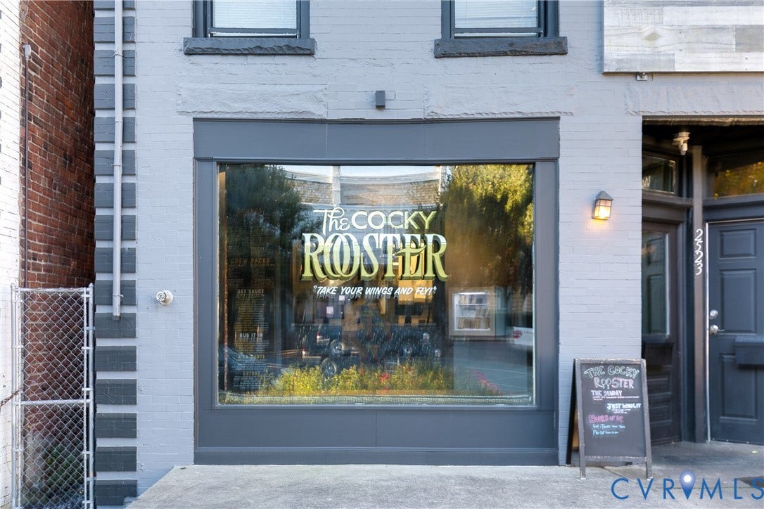 2523 W Main Street, The Fan, Richmond, VA 23220 Stone facade with a large storefront window, dark-framed entry door, and exterior wall sconce