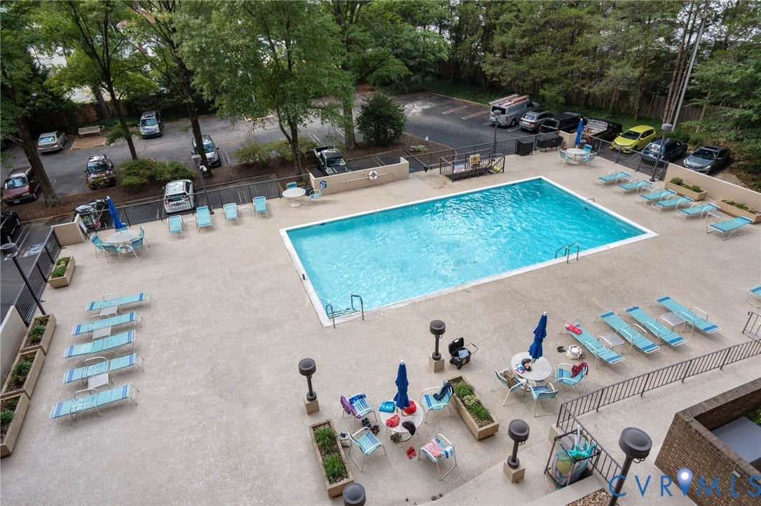 2956 Hathaway Road, #U407, Richmond, VA 23225 Balcony view! Expansive outdoor pool area featuring a rectangular swimming pool, surrounding concrete deck, and adjacent open-air parking