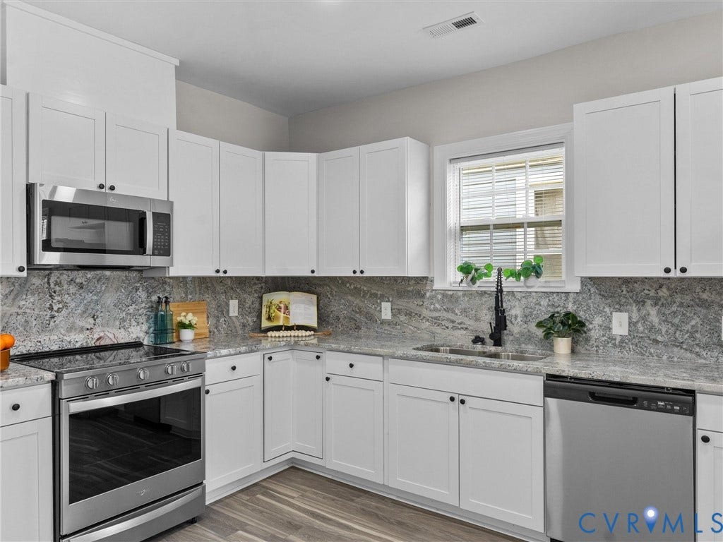 3059 Decatur Street, Richmond, VA 23224 White cabinetry, stone countertops, stainless steel appliances, wood-finish flooring, and a single basin sink with a black pull-down faucet