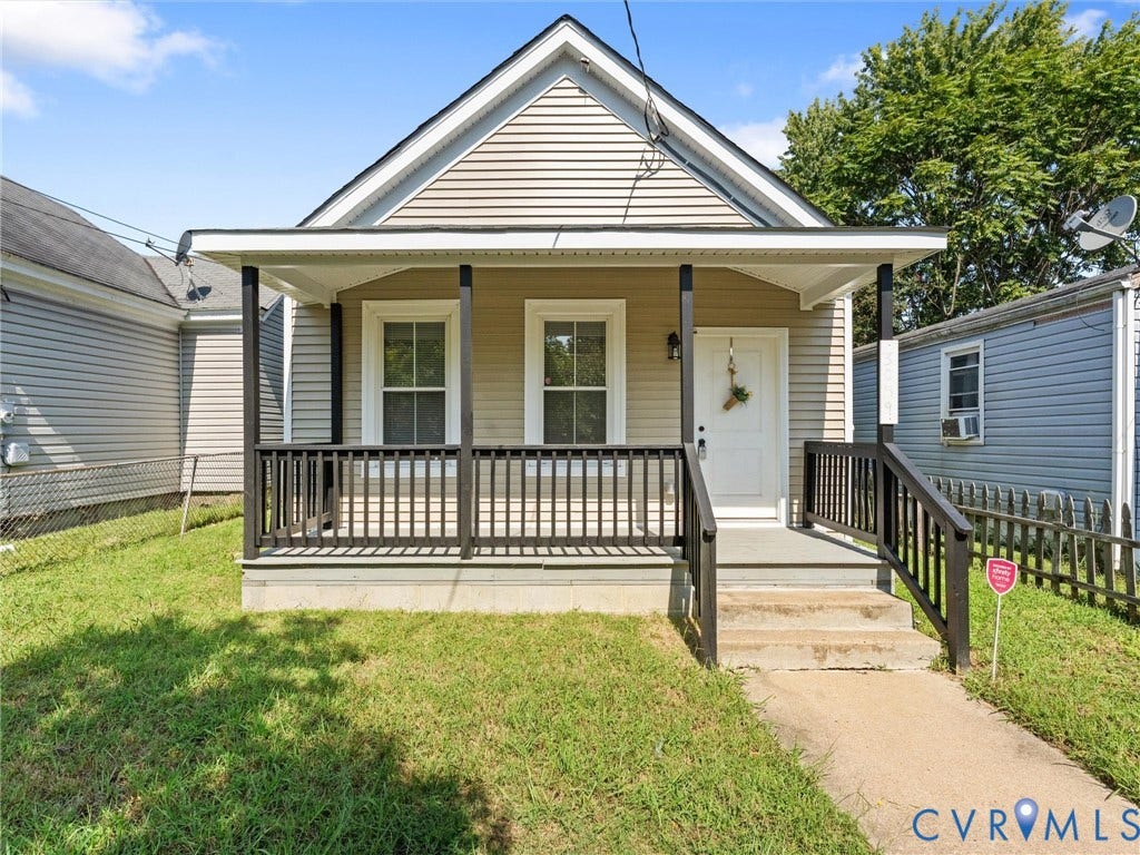 3059 Decatur Street, Richmond, VA 23224 Front facade featuring horizontal siding, a covered porch with black railings, a white entry door, and a concrete walkway