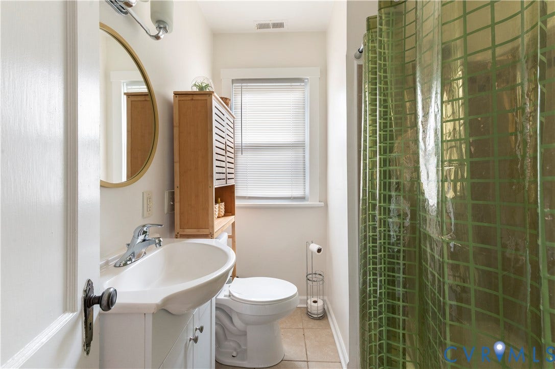 613 Rothesay Road, City Stadium, Richmond, VA 23221 White vanity with integrated sink, chrome faucet, and gold-framed circular mirror