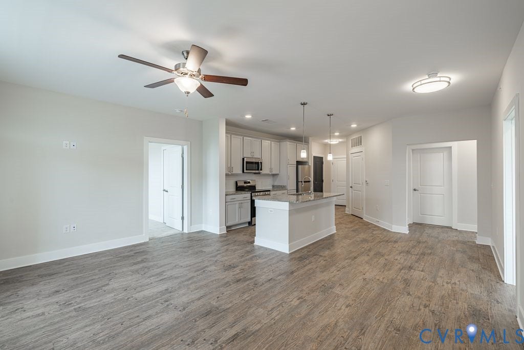10530 Stony Bluff Drive, #102, Stony Run Condos, Ashland, VA 23005 Open-concept living space featuring wood-finish flooring, a contemporary kitchen with light cabinetry, stainless steel appliances, and a central island with pendant lighting