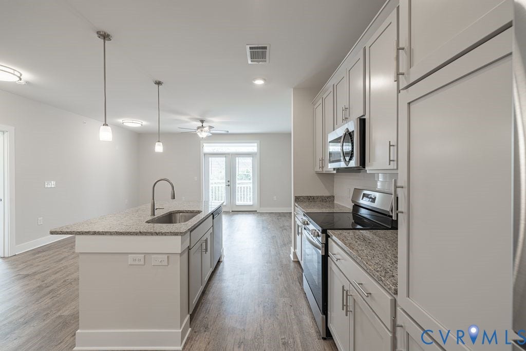 10530 Stony Bluff Drive, #102, Stony Run Condos, Ashland, VA 23005 Kitchen featuring a large island with an undermount sink, granite countertops, wood-finish flooring, white cabinetry, and stainless steel appliances