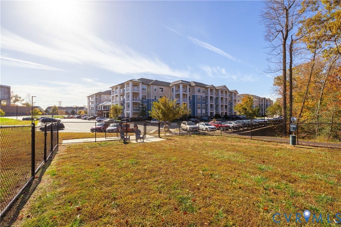 10530 Stony Bluff Drive, #102, Stony Run Condos, Ashland, VA 23005 Fenced green space with a paved walking path, adjacent to a parking area and multi-story residential buildings
