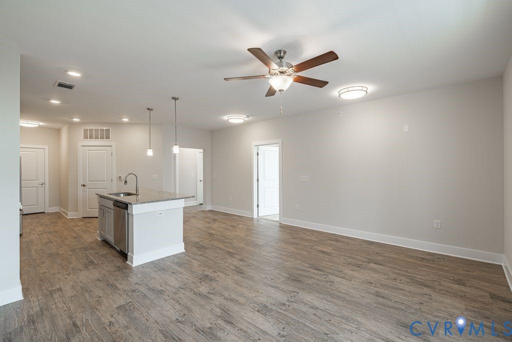 10530 Stony Bluff Drive, #102, Stony Run Condos, Ashland, VA 23005 Open concept living area featuring wood-finish flooring, a kitchen island with stone countertop, stainless steel appliances, and a ceiling fan with integrated lighting
