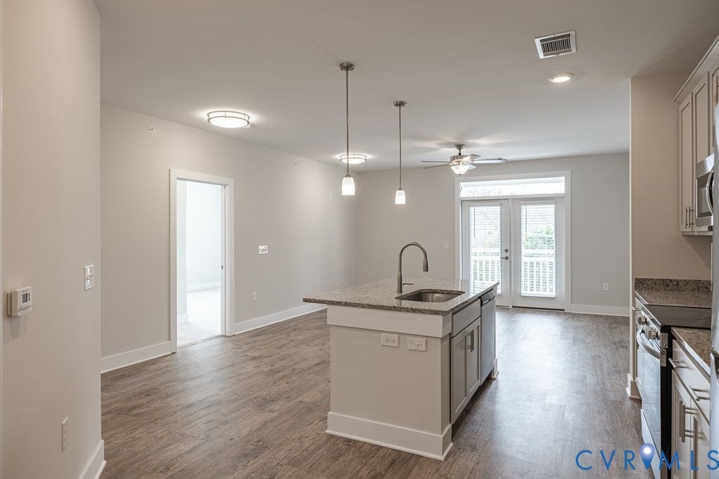 10530 Stony Bluff Drive, #102, Stony Run Condos, Ashland, VA 23005 Spacious room featuring wood-finish flooring, a kitchen island with sink, pendant lighting, ceiling fan, and double patio doors