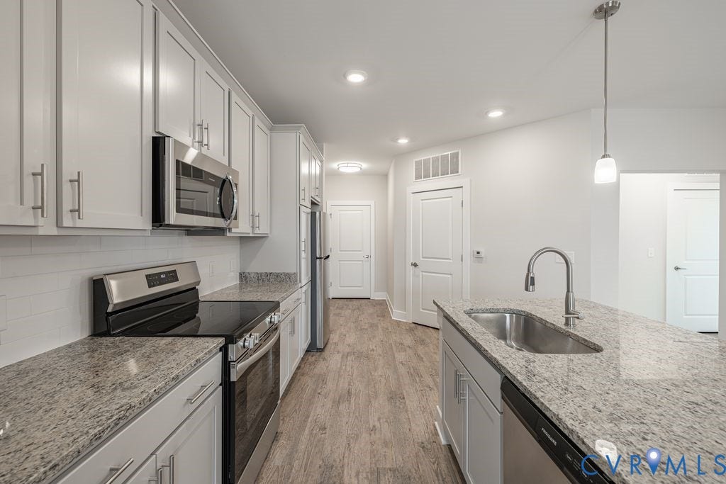 10530 Stony Bluff Drive, #102, Stony Run Condos, Ashland, VA 23005 Kitchen featuring wood-finish flooring, white cabinetry, stainless steel appliances, speckled countertops, and a subway tile backsplash