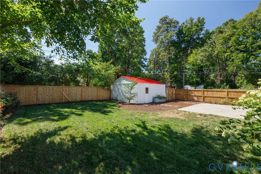 4919 Park Avenue, Near West End, Richmond, VA 23226 Private backyard featuring a wood privacy fence, a storage shed with a red roof, a paver patio, and a grass lawn