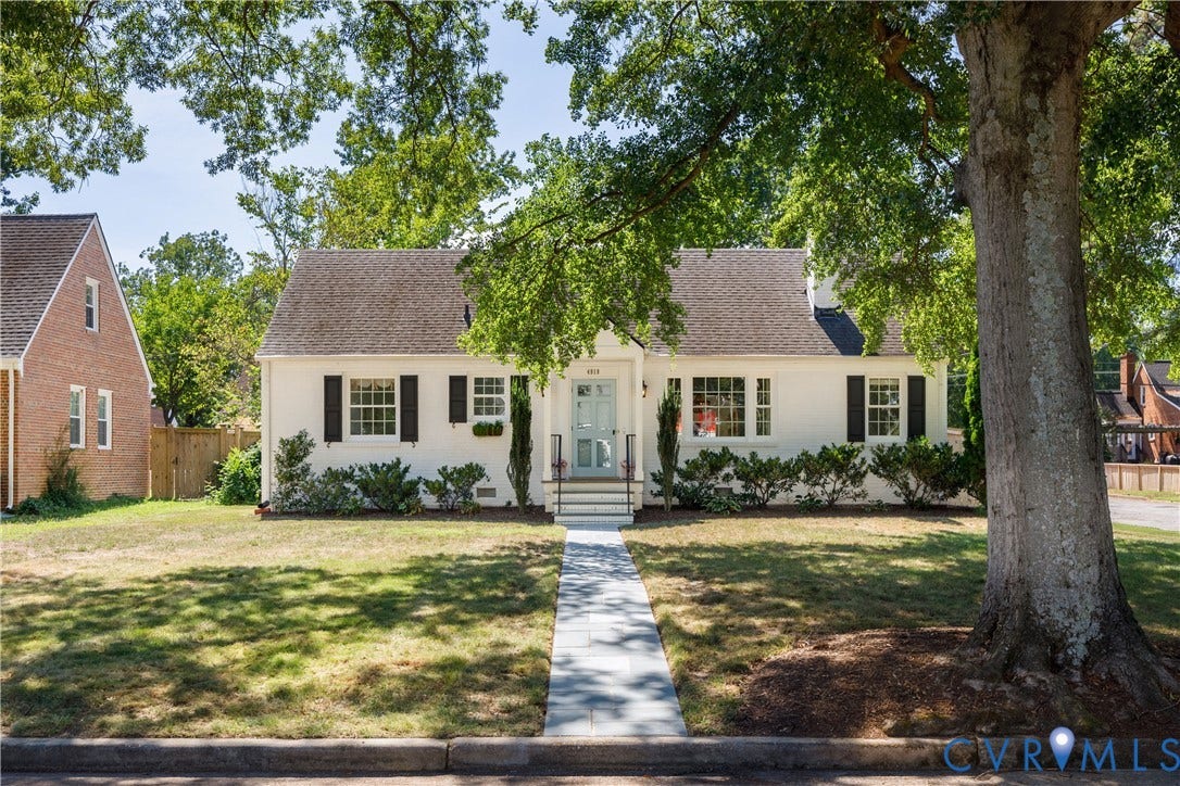 4919 Park Avenue, Near West End, Richmond, VA 23226 White facade with dark shutters, light blue front door, front yard with mature trees, and a paved walkway